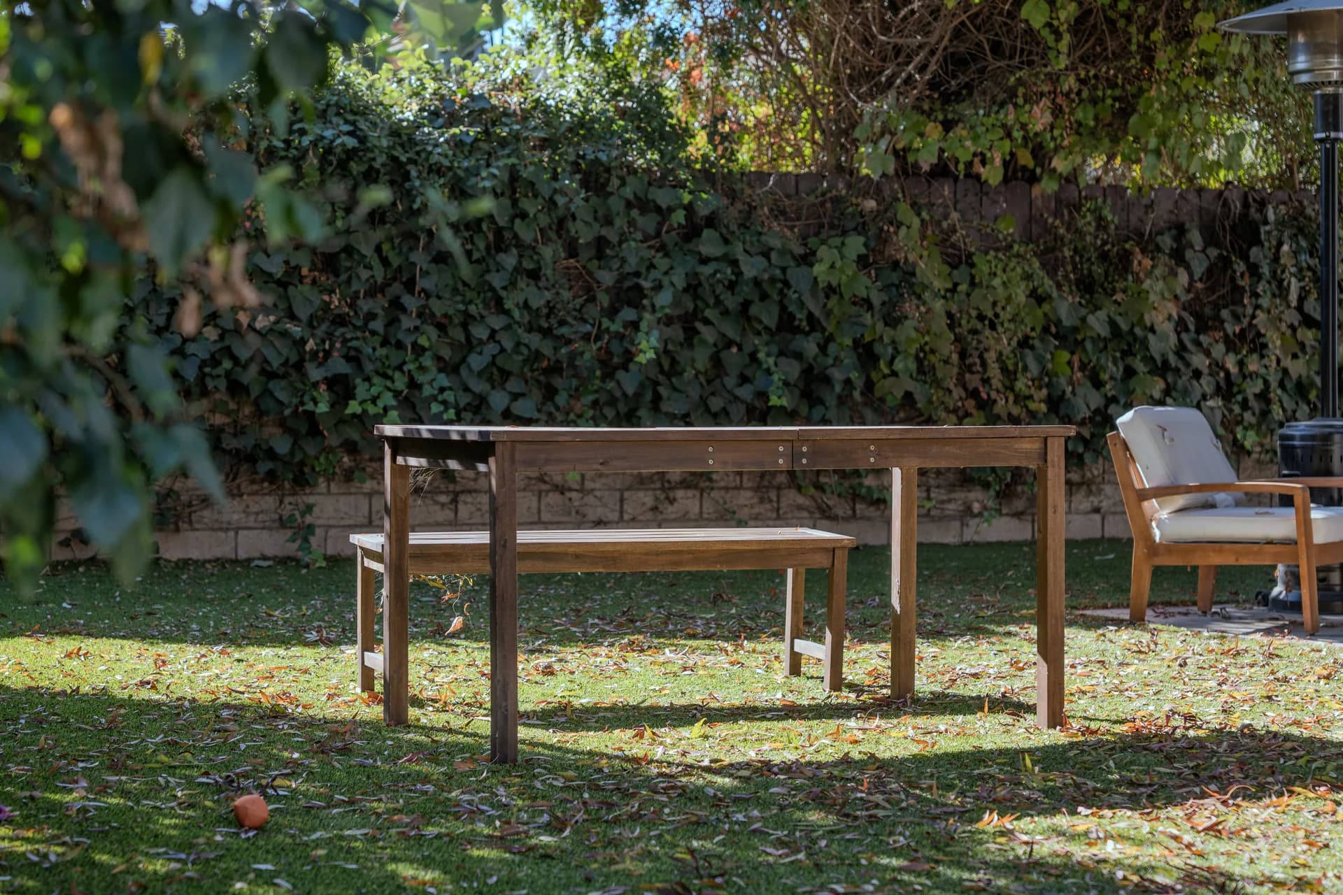 Wooden table and benches surrounded by leafy hedges