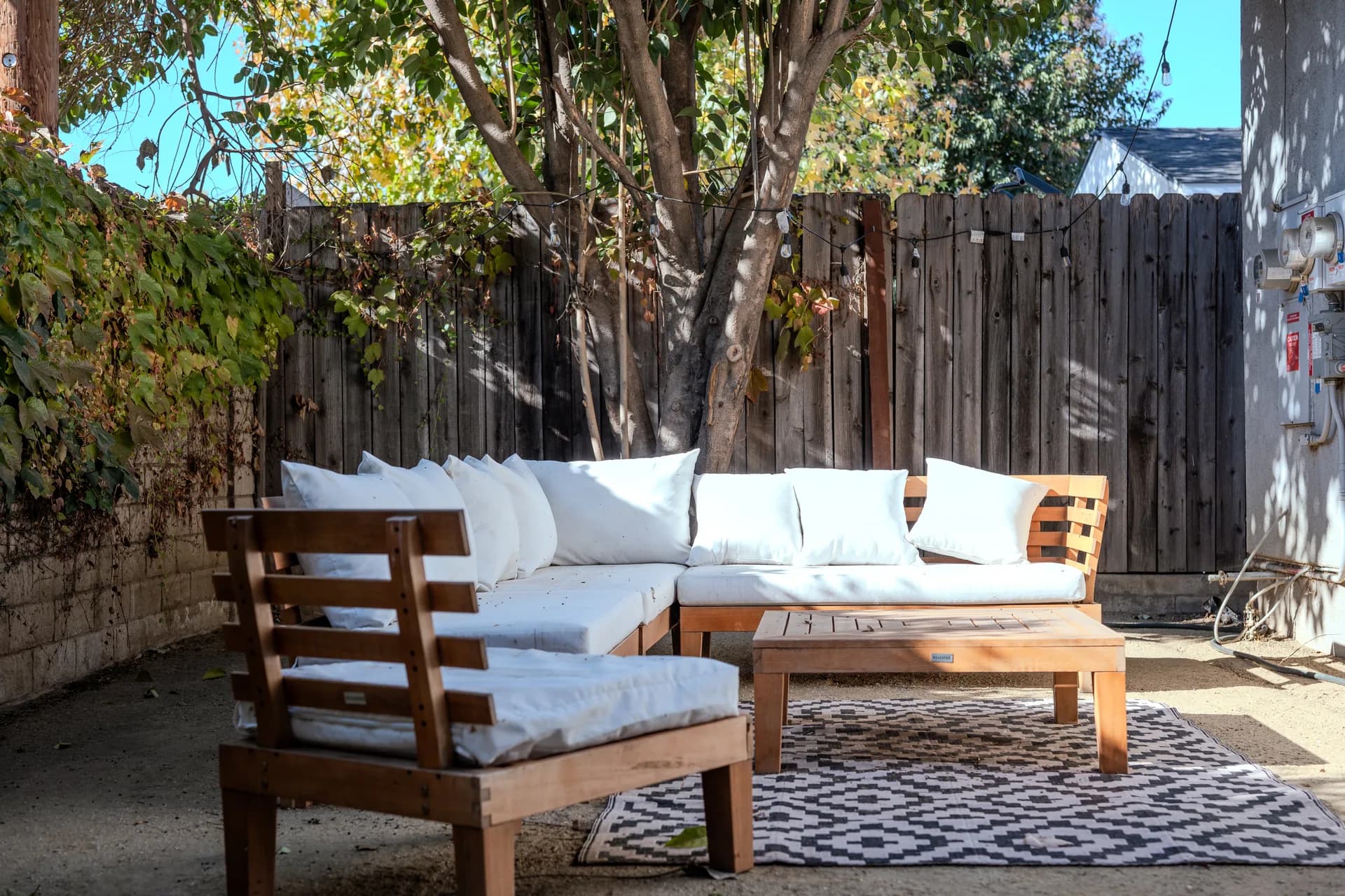 Pale cushioned outdoor sofa and wooden coffee table in the garden