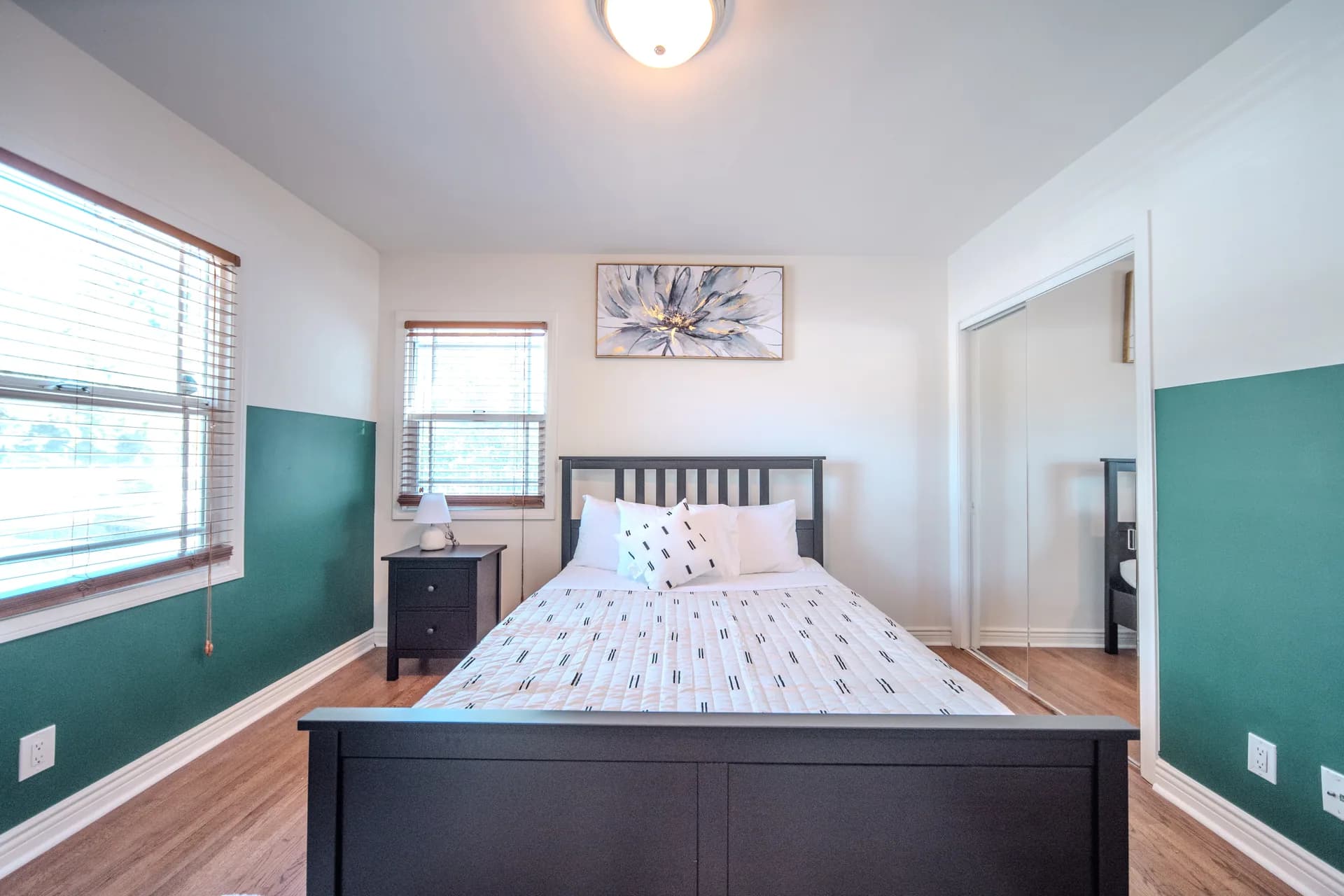Bedroom with patterned bedding, a large window, and teal accent wall