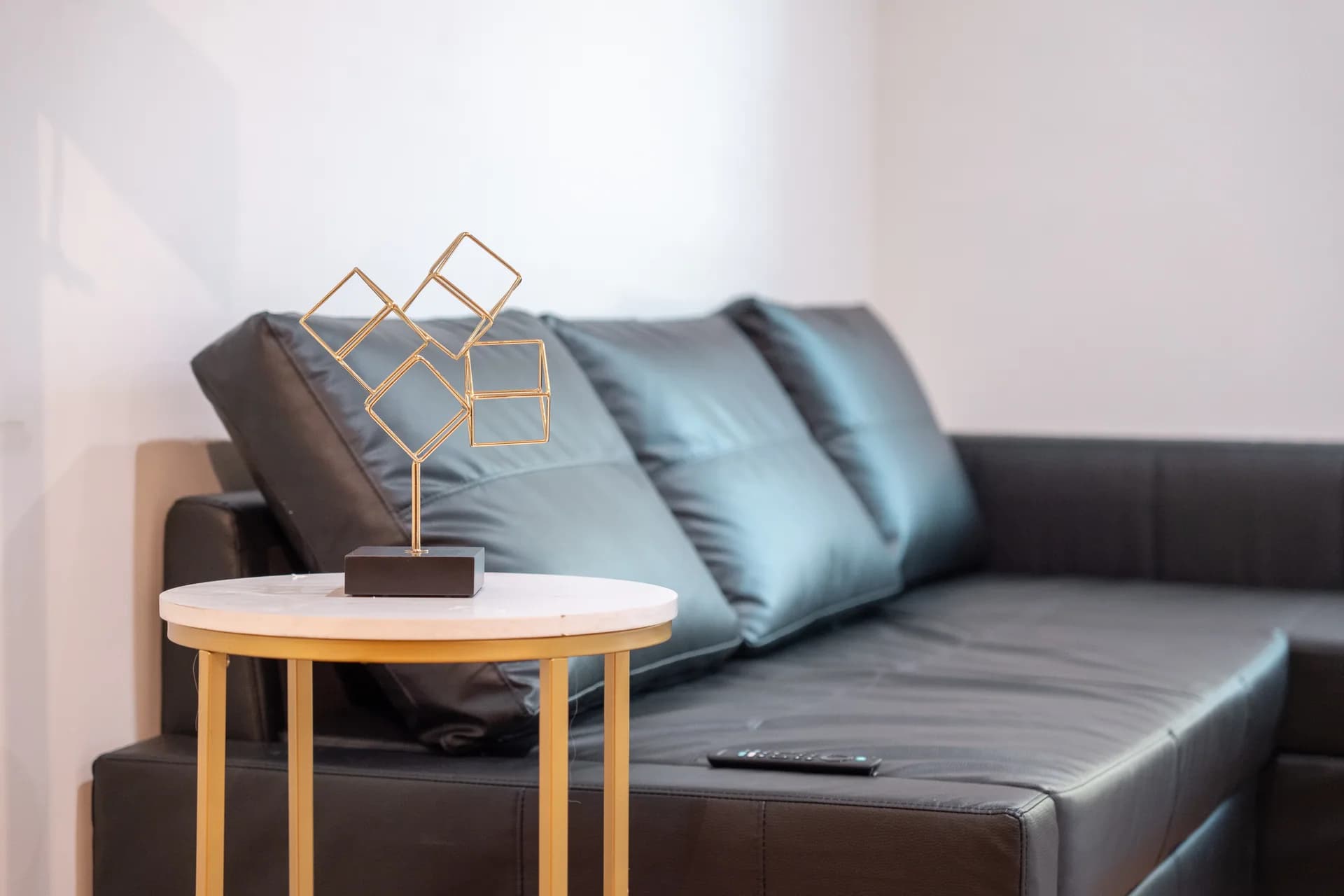 Dark living room sofa beside a round table and geometric lamp